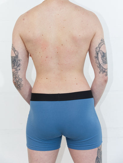 Person from behind wearing blue packing boxers in front of a white background